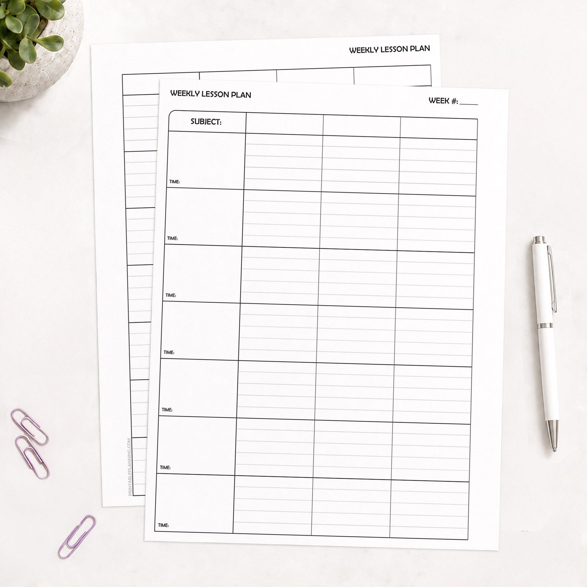 Two White Weekly Lesson Plan Pages for Teachers - Printable PDF sheets with black printed grid lines, arranged on a light surface with a white pen, purple paperclips, and a small plant in the corners.