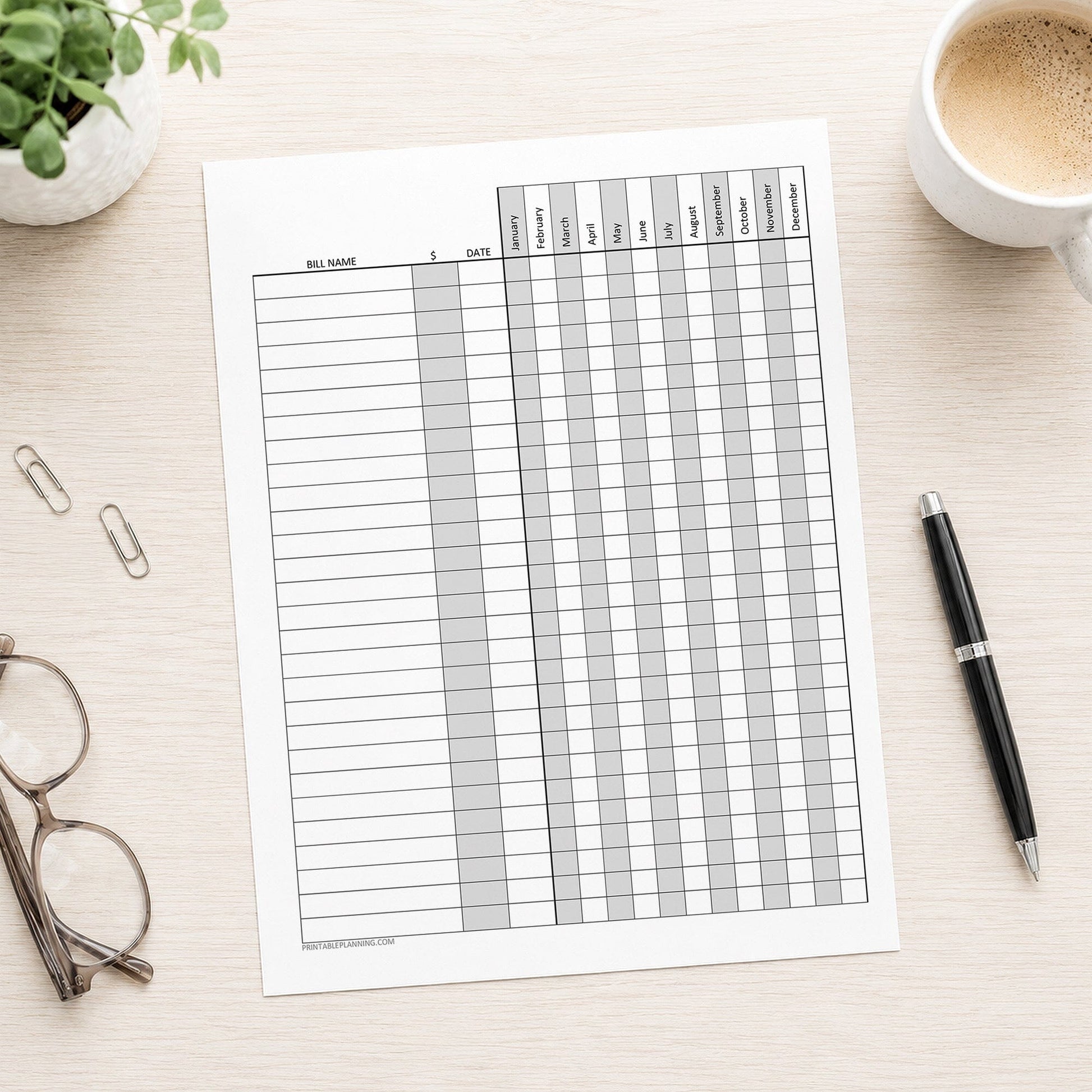 Yearly Bill Payment Tracker with Amount Column - Printable Annual Bill Checklist shown on a desk with glasses, a plant, coffee, and a pen.