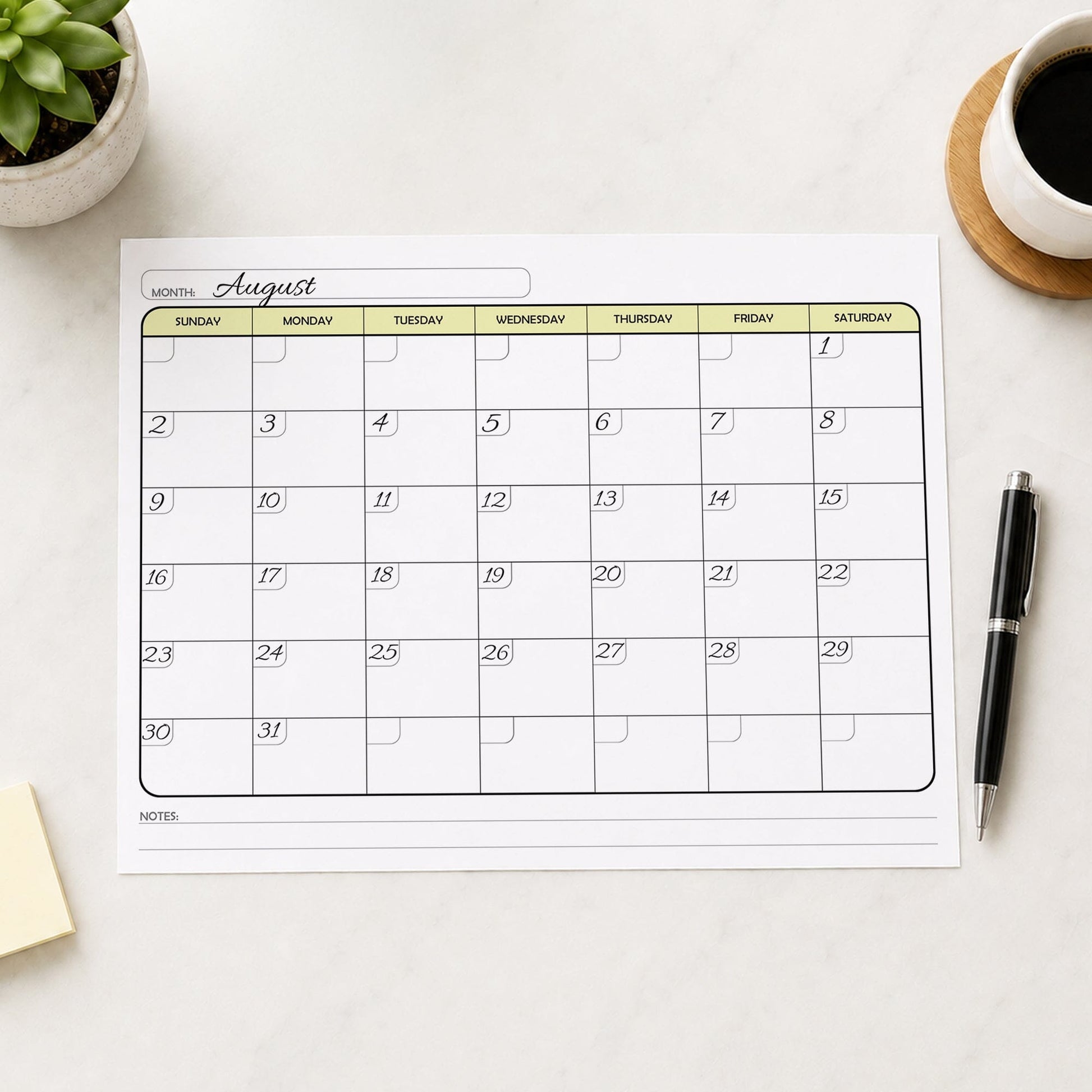 A printed Undated Monthly Calendar - Yellow Full-Page Planner (printable) page shown with example writing on a desk with a plant, sticky notes, coffee, and a pen.