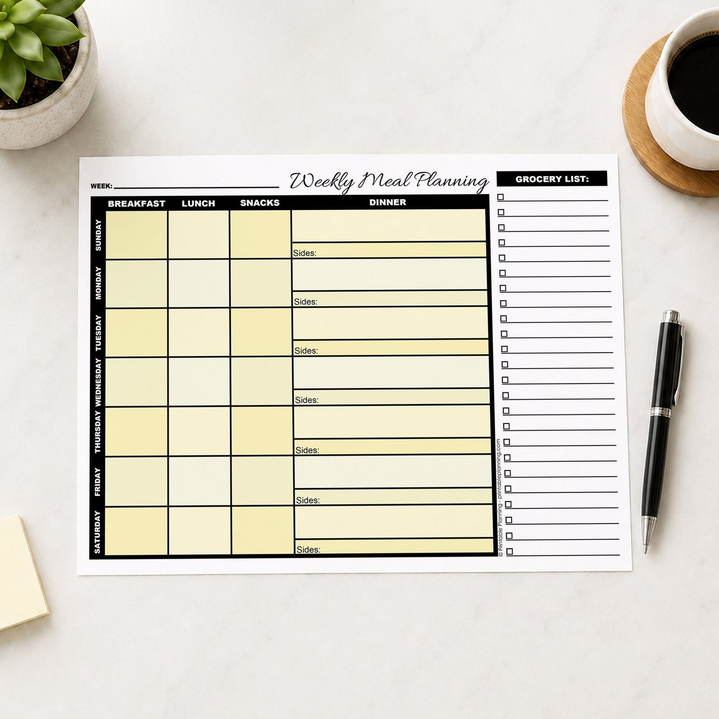 A printed Yellow Weekly Meal Planner with Grocery List (printable page) shown on a table with a plant, sticky notes, coffee, and a pen.
