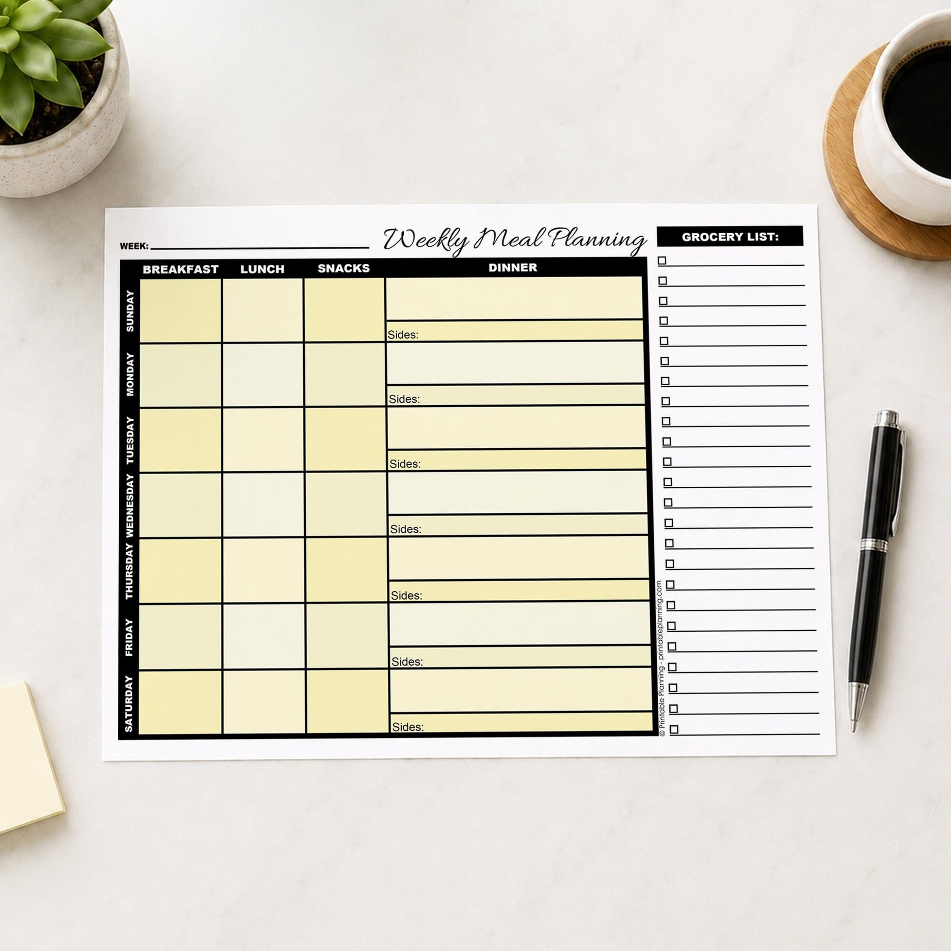 A printed Yellow Weekly Meal Planner with Grocery List (printable page) shown on a table with a plant, sticky notes, coffee, and a pen.