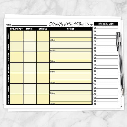 A printable Yellow Weekly Meal Planner with Grocery List shown on a marble surface with a pen.